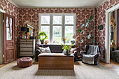 Living room with patterned wallpaper, leather sofa and wooden chest as a coffee table