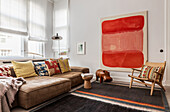 Modern living room with brown sofa, decorative throws and large red wall art