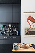 Modern black kitchen with flamingo wall poster and wooden board with bread