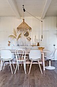 Dining room with wooden table, white chairs and rattan hanging lamp