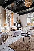 Living room with piano, dark-painted wooden beamed ceiling and jute carpet