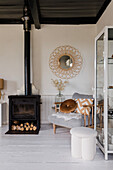 Cosy corner with wood-burning stove, armchair and round mirror with rattan frame