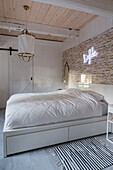 Bedroom with stone wall, neon sign and wooden beamed ceiling