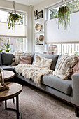 Brightly furnished living room with grey sofa and hanging green plants