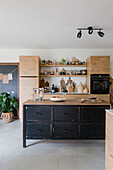 Kitchen with black cooking island and open wooden shelves