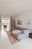 Bright living room with light grey corner sofa and white floorboards