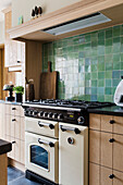 Küche mit Holzschränken, grünen Wandfliesen und cremefarbenem Herd