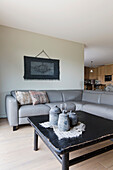 Light grey corner leather sofa with dark wooden table and tapestry