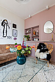 Wohnzimmer mit Rattansessel, Glas-Couchtisch und farbenfrohem Blumenstrauß