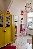 Yellow vintage wardrobe and colourful decorative elements in the children's room