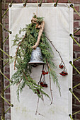 Wall decoration made of metal bell with juniper branches and berries