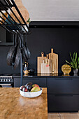 Moderne Küche mit schwarzen Fronten und Kücheninsel mit Holzarbeitsplatte