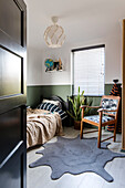 Einzelbett und Leseecke im Schlafzimmer mit grüner Wandgestaltung und klecksförmigen Teppich