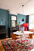 Dining room with blue-green wall, round dining table and patterned carpet