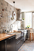 Tiled kitchen with black cabinets and wooden worktop