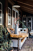 Gemütliche Terrasse mit weißer Sitzbank und dekorativer Vase