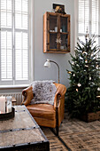 Weihnachtlich dekoriertes Wohnzimmer mit Lederstuhl und Tannenbaum