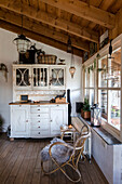 Landhausküche mit Holzbalkendecke, Holzmöbeln und Rattansessel