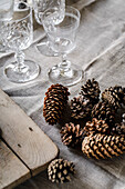 Table decoration with pine cones and crystal glasses on a linen cloth