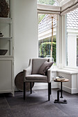 Leseecke mit grauem Sessel und rundem Beistelltisch am Fenster