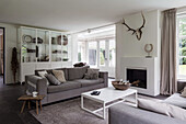 Modernes Wohnzimmer mit grauem Sofa, Kamin und weißen Regalen