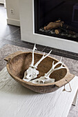 Wooden bowl with animal bones on a white side table in front of the fireplace