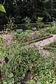 Flower bed with benches in the park-like garden in summer