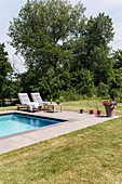 Sunny pool area with sun loungers and flower pots