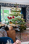 Christmas tree in the living room with floral wallpaper and dark curtains