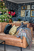 Leather couch with cushions, blanket and Christmas tree in the background