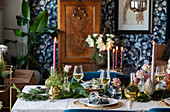 Gedeckter Esstisch mit Kerzenlicht, Blumen und Pflanzen