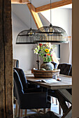 Rustic dining table with cage pendant lights and floral arrangement