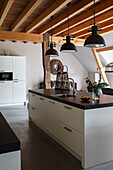 Modern kitchen island with black worktop and pendant lights