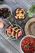 Sommerlicher Picknicktisch mit Wassermelonenspießen, Erdbeer-Dessert und Salat