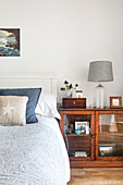 Bed next to cabinet with glass doors, glass lamp and decorative elements