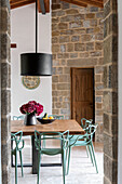 Dining room with stone walls, wooden table and modern chairs