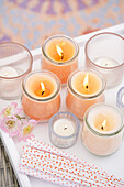 Tea lights and scented candles in glasses on a white tray