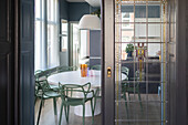 View of dining room with round table and green chairs, lead glass sliding door