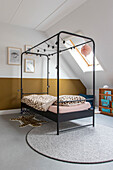 Metal four-poster bed with fairy lights, leopard bed linen in the children's room