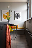 Corner bench in the dining area with yellow chairs and modern art on the walls