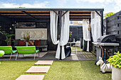 Covered patio with curtains, seating furniture and gas barbecue