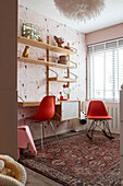 Work area in the children's room with red chairs, wall shelves and oriental rug