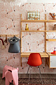 Workplace in the children's room with wooden desk and red chair in front of flamingo wallpaper