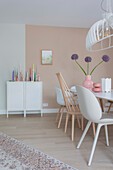 Dining room with pink accent wall, white furniture and floral decorations