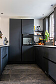 Modern kitchen with dark cabinets and grey tiled floor