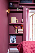 Built-in shelving in mauve-colored bedroom with decorative objects and dried flowers