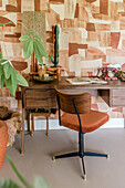 Retro-style desk with geometric wallpaper and decorative objects