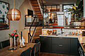 Open-plan dining room with modern kitchen and wooden staircase