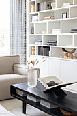 Modern living room with black coffee table and white built in wall shelf