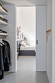 Walk-in wardrobe with view through sliding door into the bedroom